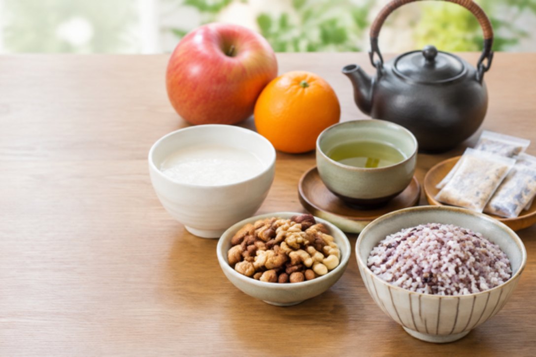 果物、緑茶、甘酒、ナッツ、雑穀を木のテーブルに並べた食卓