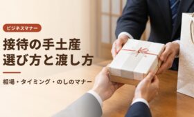 和室のテーブル越しに、両手で手土産の箱を取引先へ渡す手元。接待の手土産の選び方と渡し方